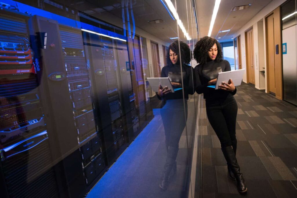 Woman looking at a computer leaning against a wall.