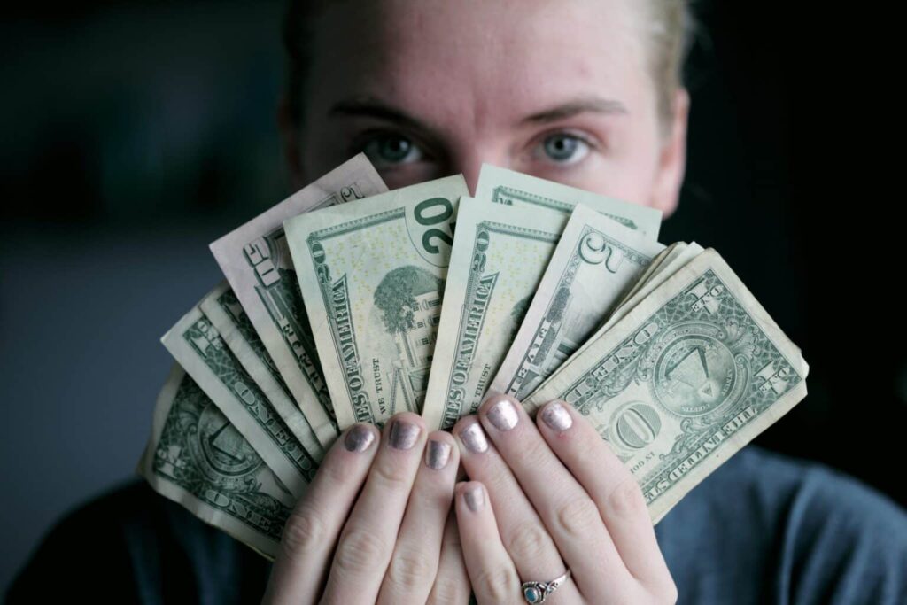 A person fans out U.S. dollar banknotes in front of their face.