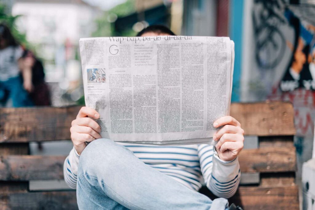 Man sitting on a bench reading a paper