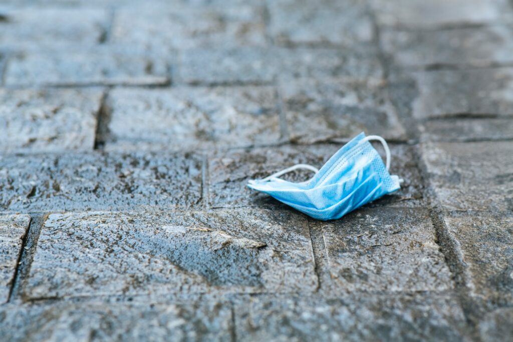 Used medical breathing mask on a stone pathway.