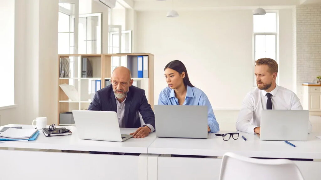 Two men and a woman work on their laptops in the office.