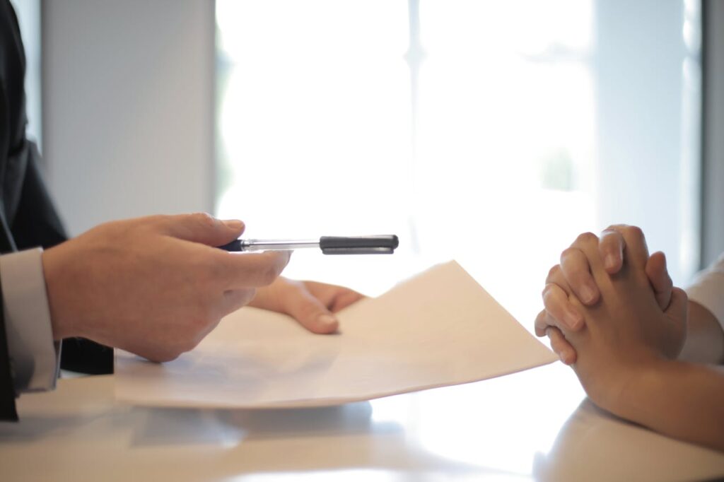 Businessman giving contract to woman to sign.