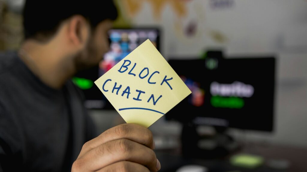 A man is holding up a note that reads “Block Chain”.