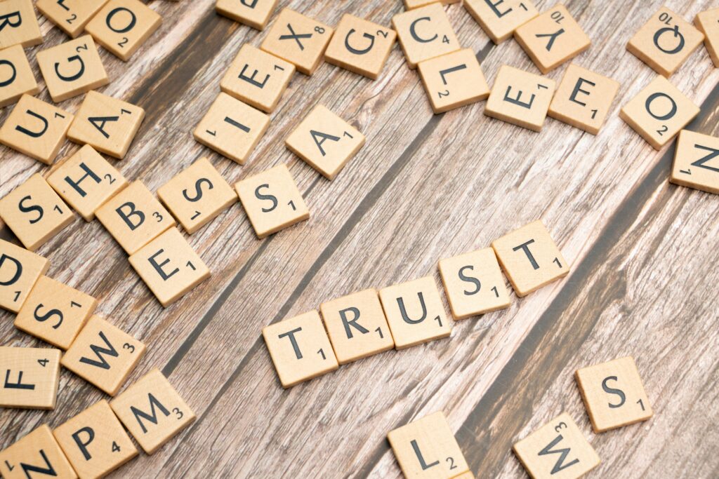 Tiles that spell the word "trust" on a wooden surface.