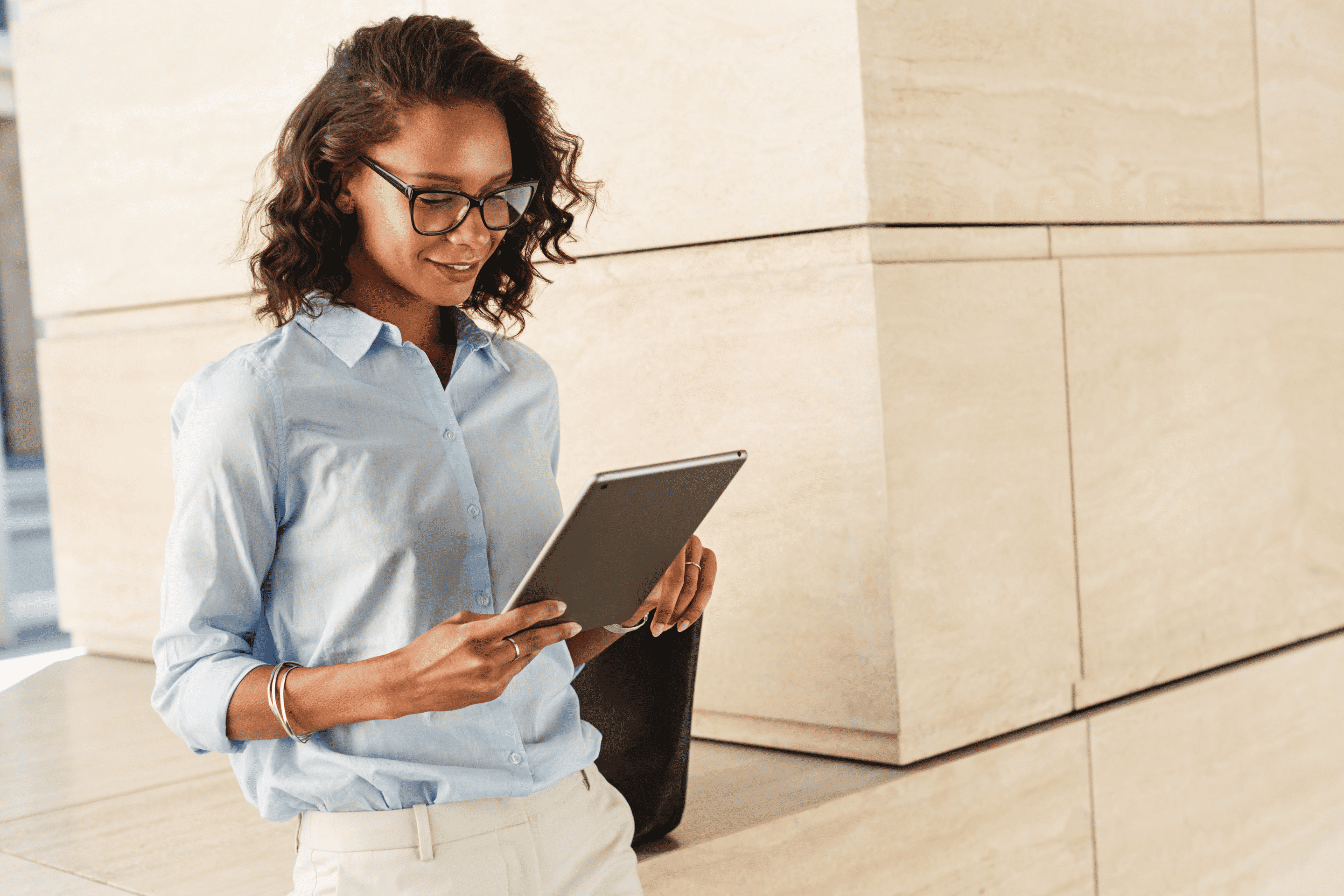 Professional woman in glasses looking at a tablet.
