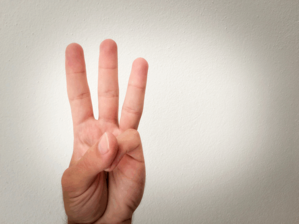 A hand shows three fingers extended, symbolizing the number three.